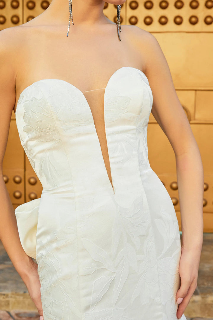 White strapless gown with a deep neckline on a blurred background