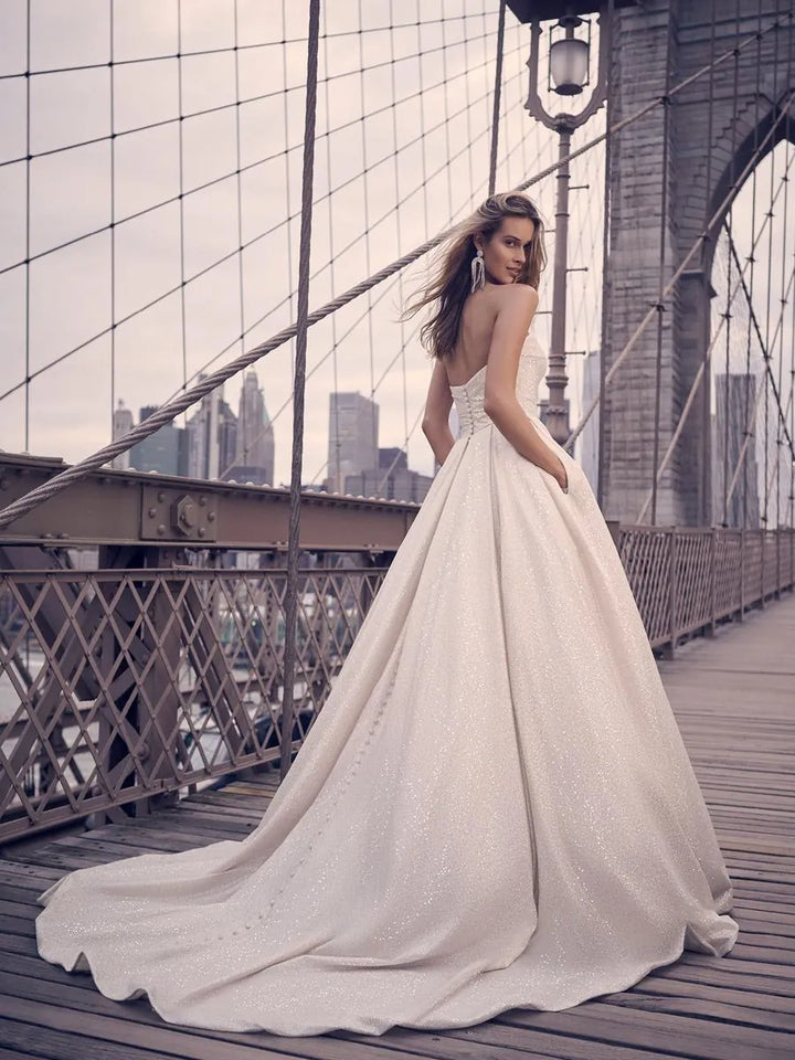 Woman in a white wedding dress standing on a bridge with a city skyline in the background