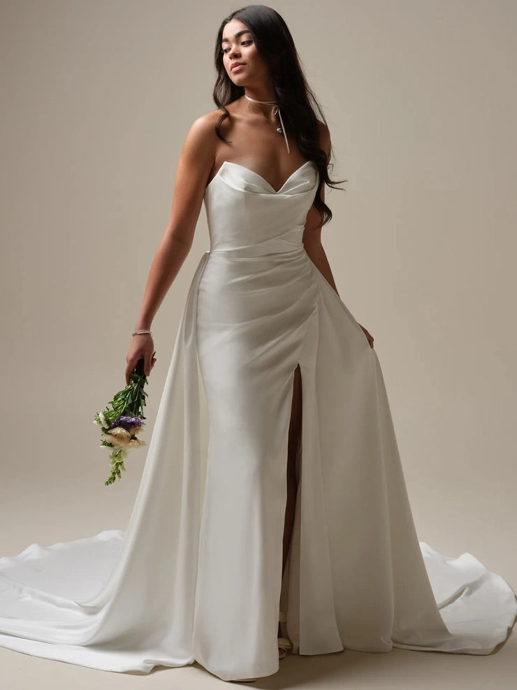 full front of maggie sottero camille ivory satin fitted wedding dress featuring a strapless v neckline, slit in the skirt, and matching overskirt