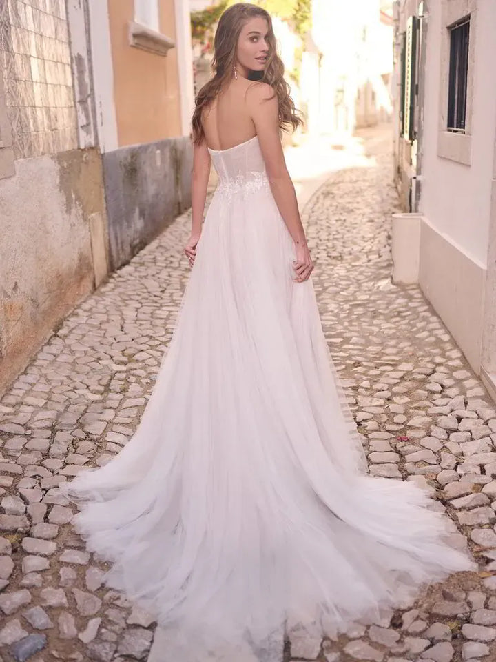 Woman in a white wedding dress standing on a cobblestone street.