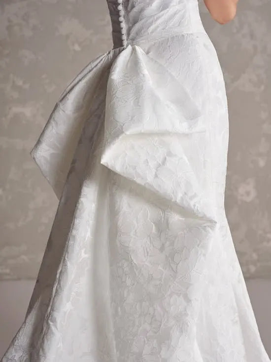 Close-up of a white lace wedding dress with a floral patterned background