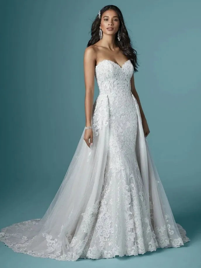 front of maggie sottero kaysen lace fitted wedding dress with strapless sweetheart neckline and matching overskirt