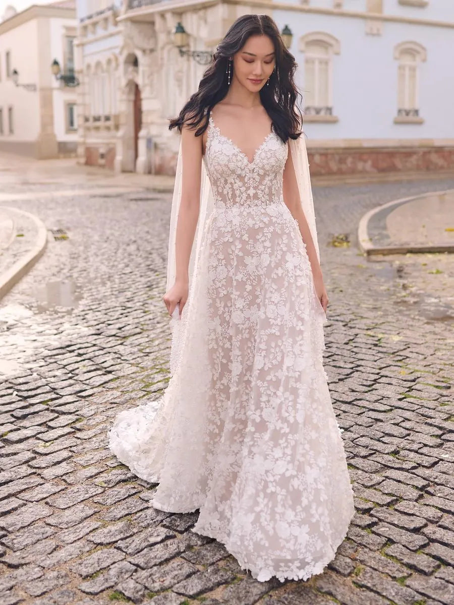 Woman in a white lace wedding dress standing on a cobblestone street.