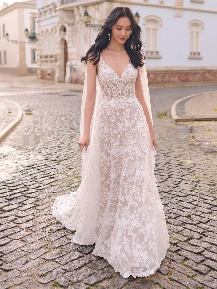 Woman in a white lace wedding dress standing on a cobblestone street.