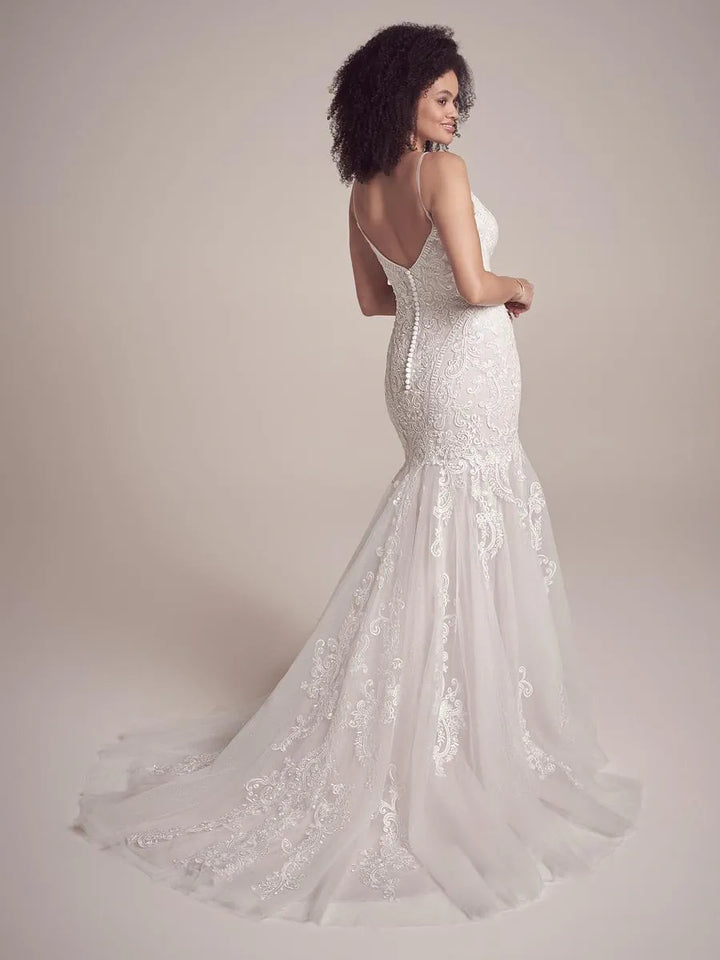 Woman wearing a white lace wedding dress against a plain background