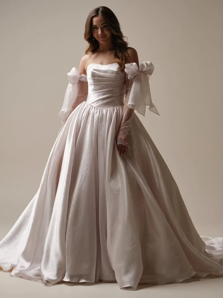 full front of maggie sottero paris organza ball gown featuring a basque waist and matching long sleeves with oversized bows
