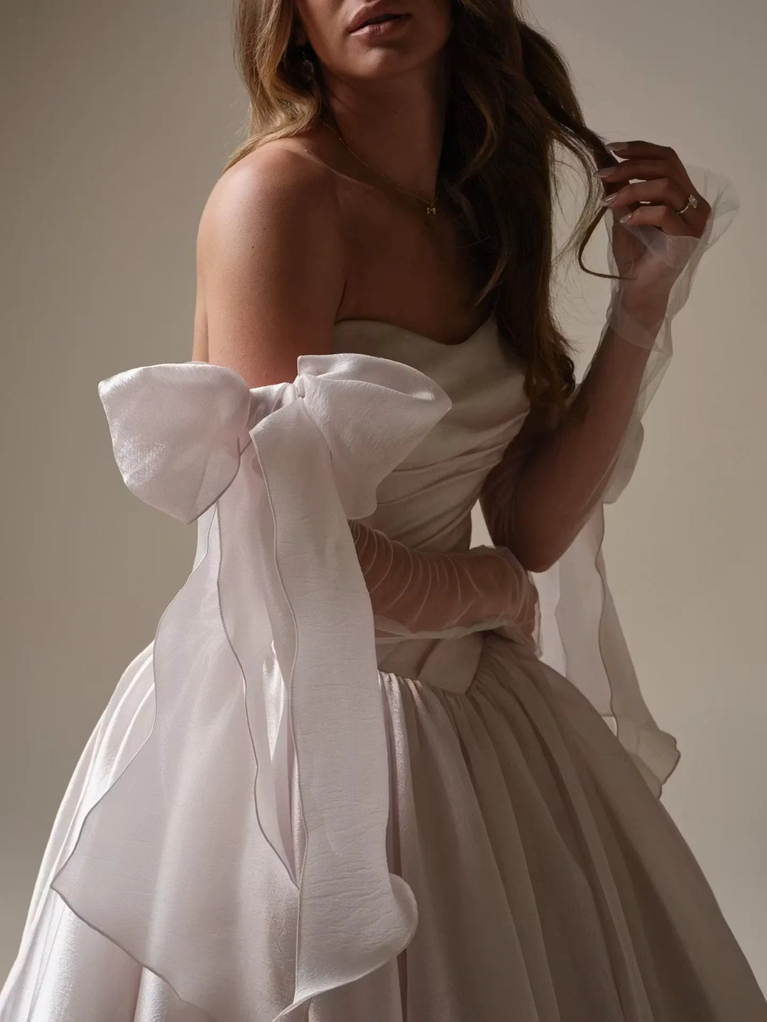 close up of maggie sottero paris organza ball gown showing the oversized bows on the matching long sleeves
