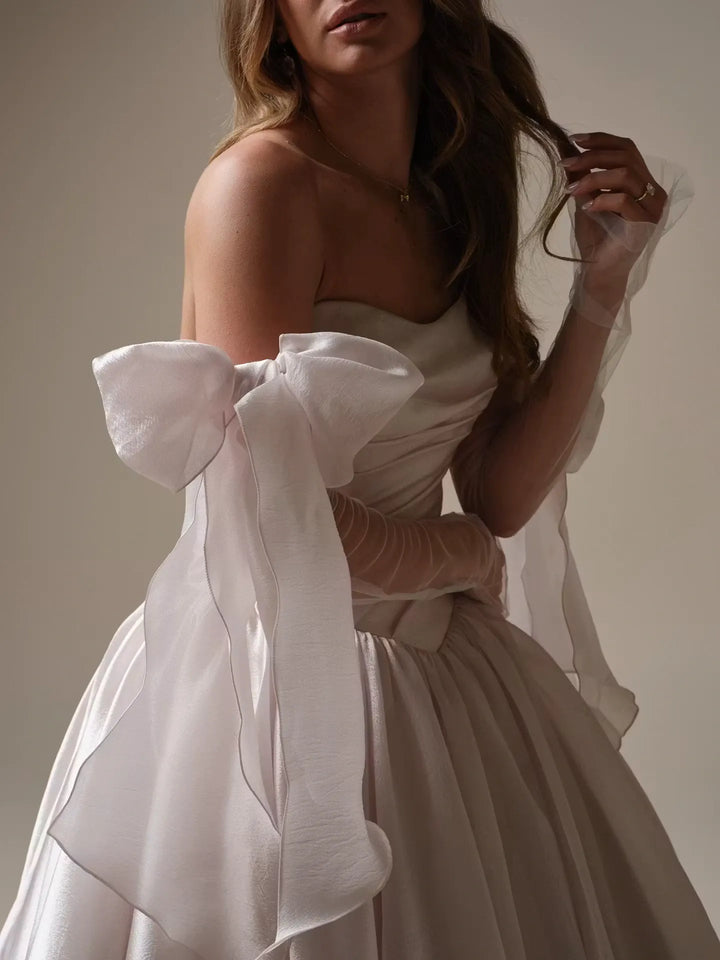 close up of maggie sottero paris organza ball gown showing the oversized bows on the matching long sleeves