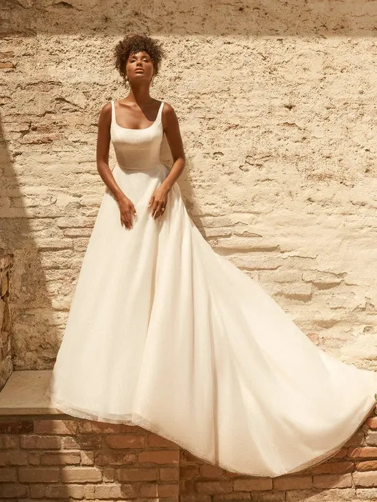 full front of maggie sottero symphony ivory tulle ball gown featuring a square neckline with a belt at the waist
