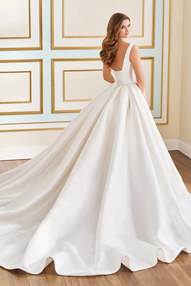 White wedding dress with a long train on a wooden floor.