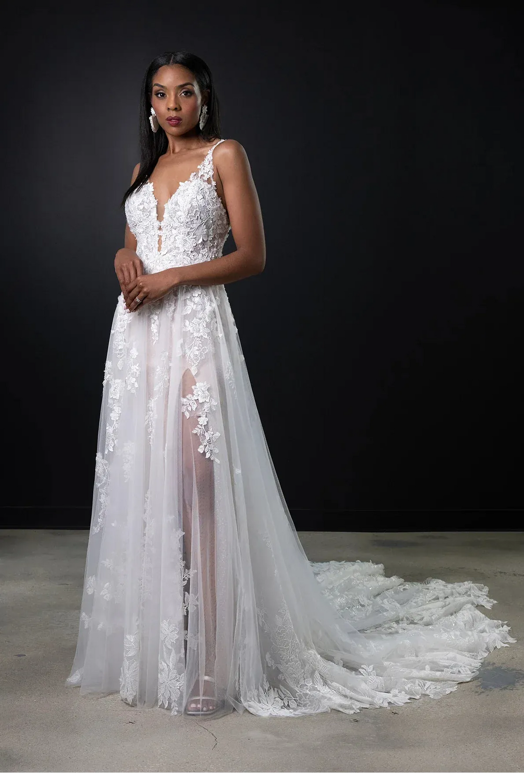 Woman wearing a white floral wedding dress against a black background