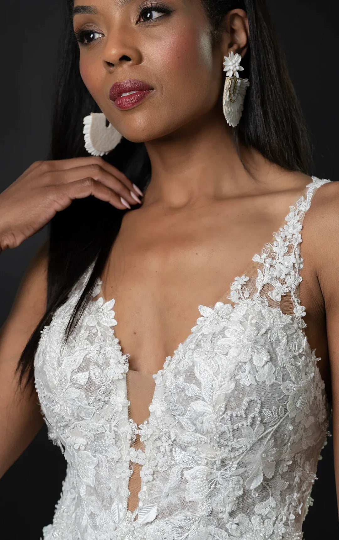 Woman wearing a white lace wedding dress against a dark background