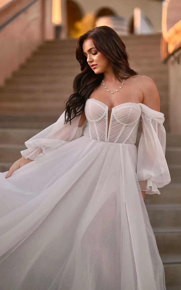 Woman in a white off-shoulder dress standing on a staircase.