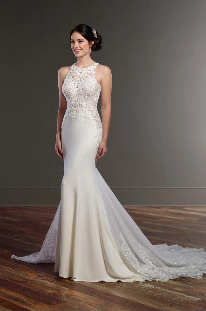 Woman wearing a white lace wedding dress on a wooden floor with a gray background