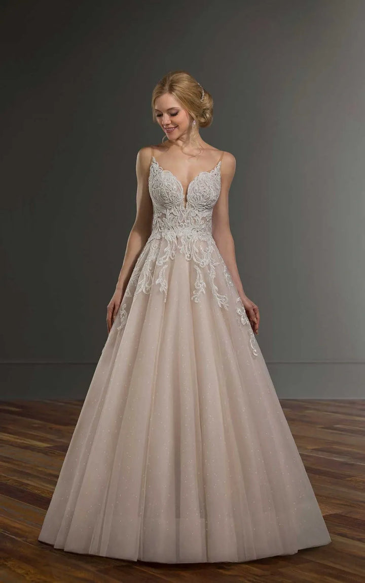 Woman wearing a beige wedding dress with lace details on a wooden floor.
