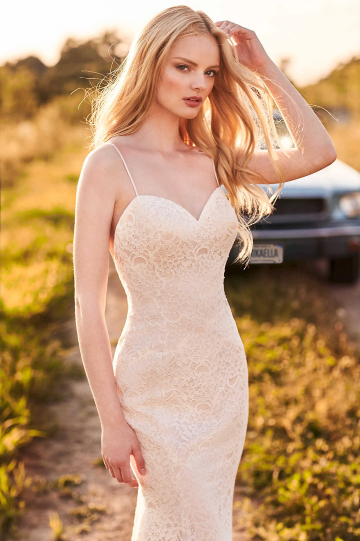 Woman in a white lace dress standing outdoors with a blurred background