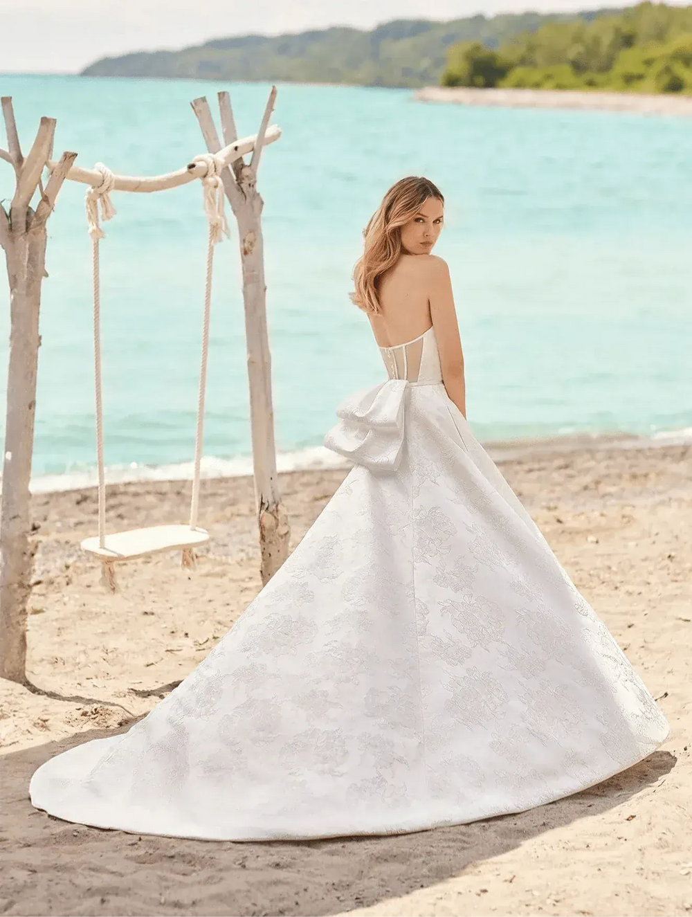 full front of mikaella m2485 ivory jacquard a-line wedding dress with a bow at the back and a chapel length train