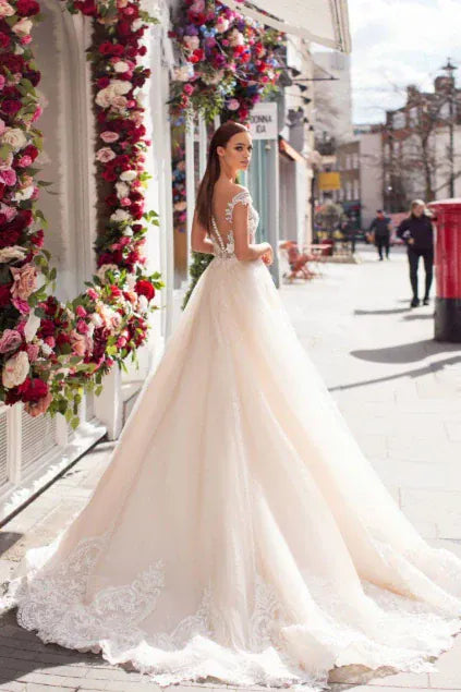 Woman in a white wedding dress standing on a city street with floral decorations.
