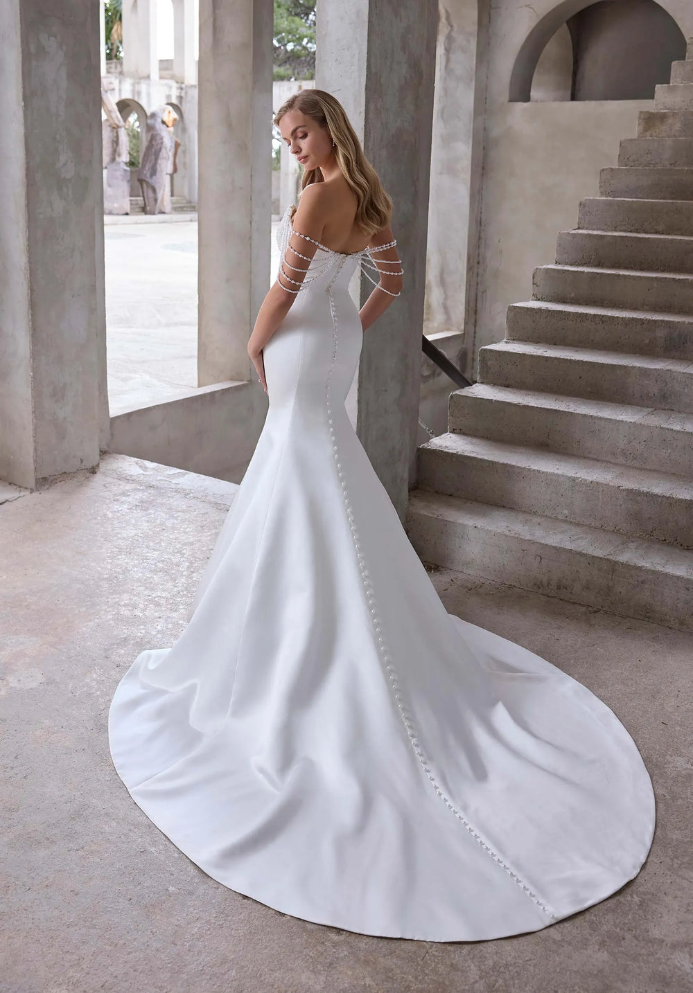 back of morilee atete ivory satin fit and flare wedding dress with buttons down the back and a chapel length train