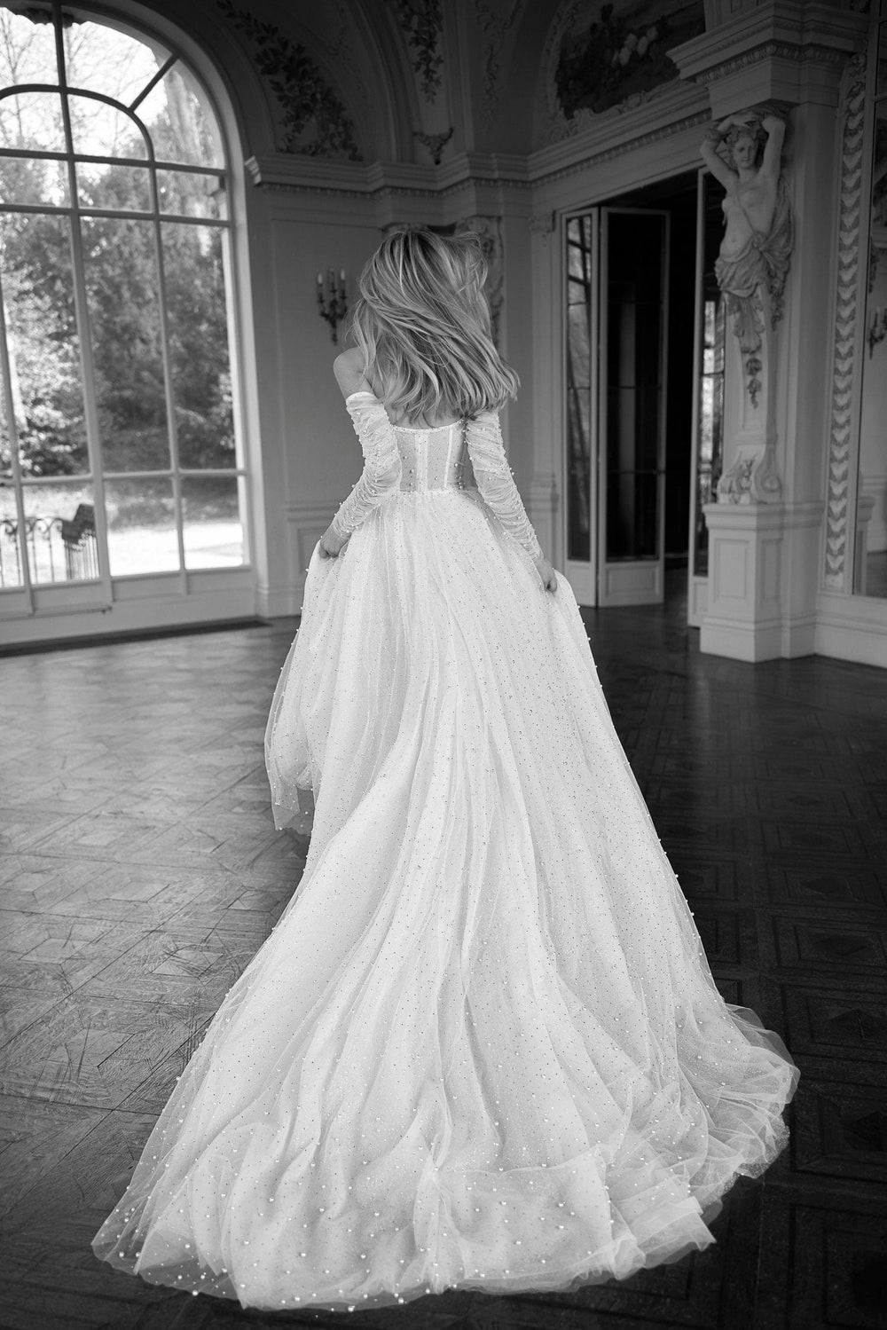 full back of netta benshabu avery ivory tulle a-line wedding dress with an off the shoulder long sleeve neckline, and a flowy train