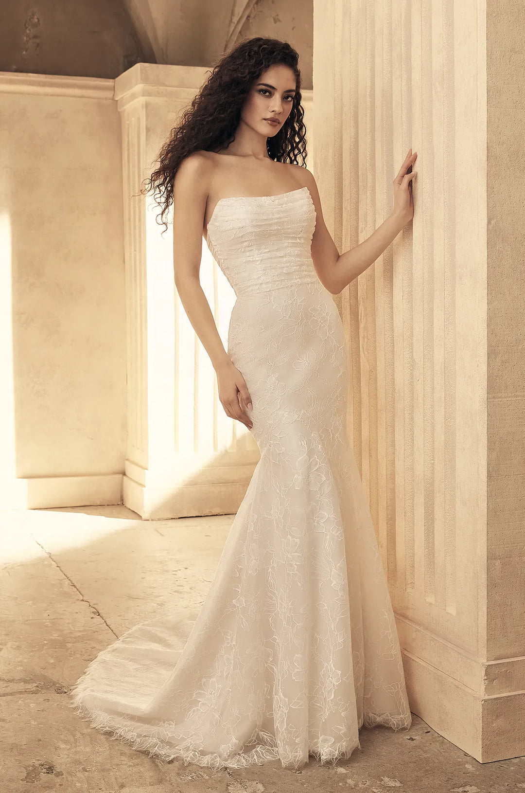 Woman in a strapless white wedding dress standing in a classical setting.