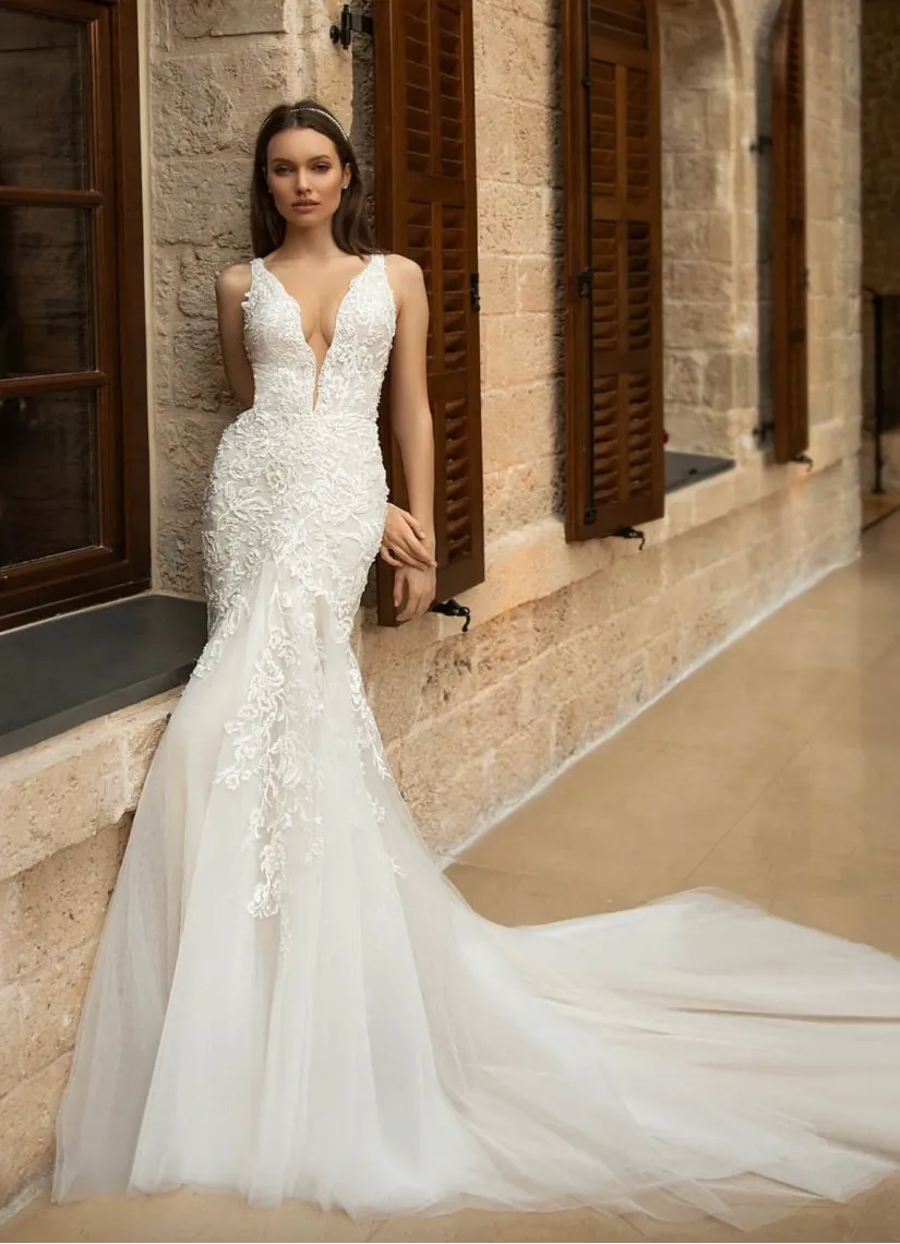 Woman in a white wedding dress standing in front of a stone building.