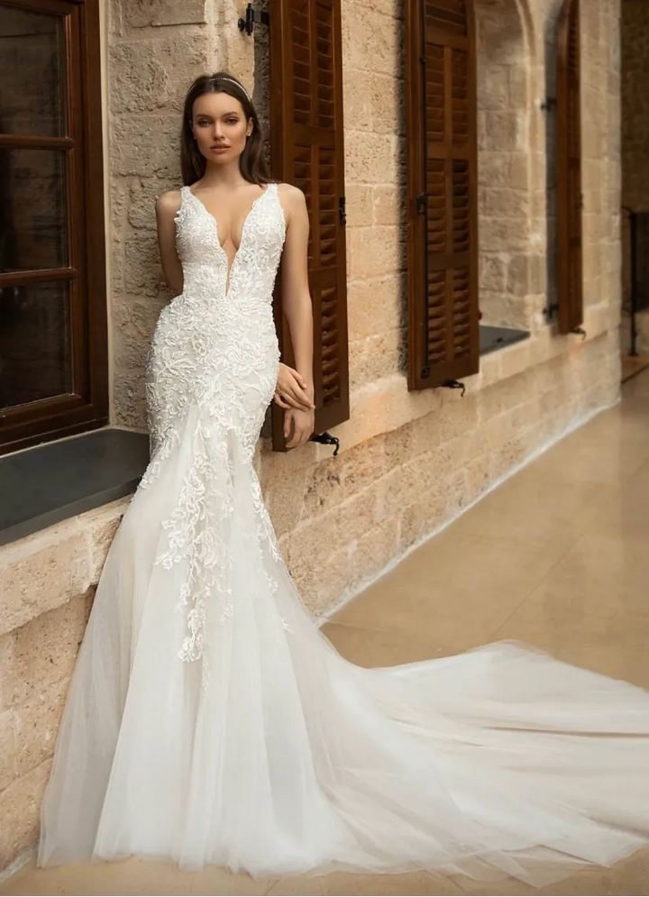 Woman in a white wedding dress standing in front of a stone building.