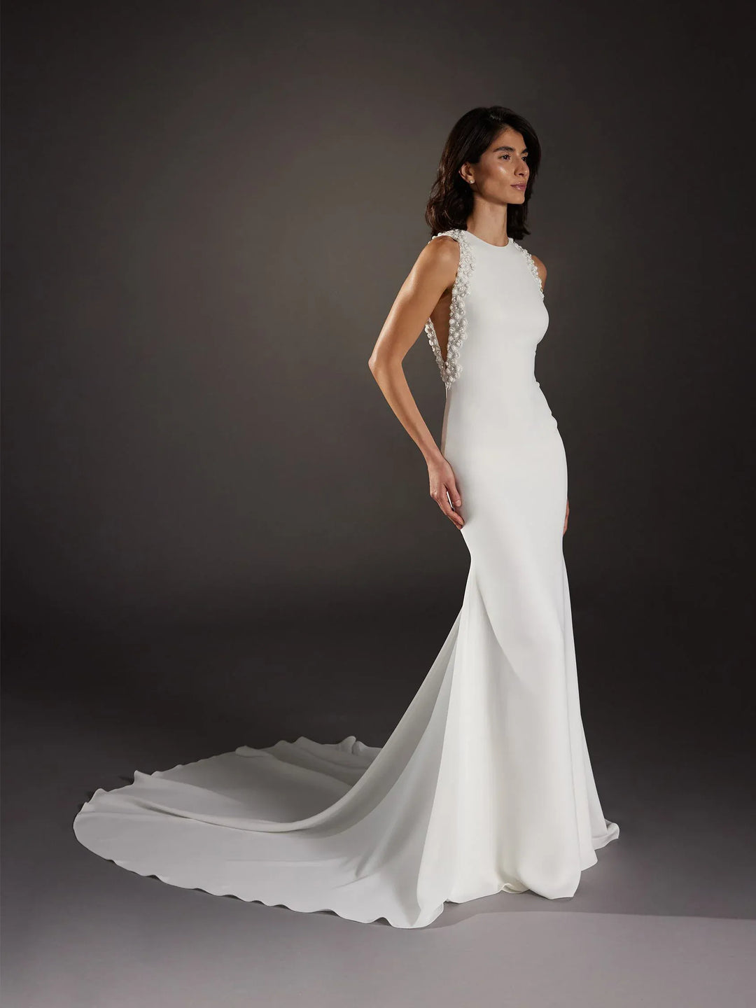 White wedding dress with a long train on a dark background