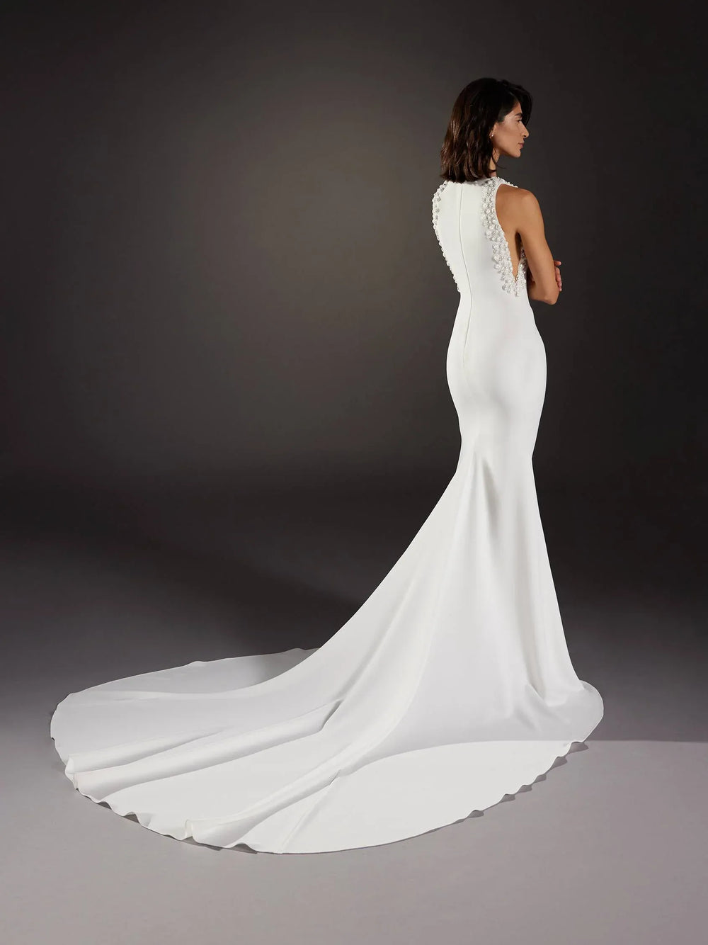 White wedding dress with a long train on a dark background