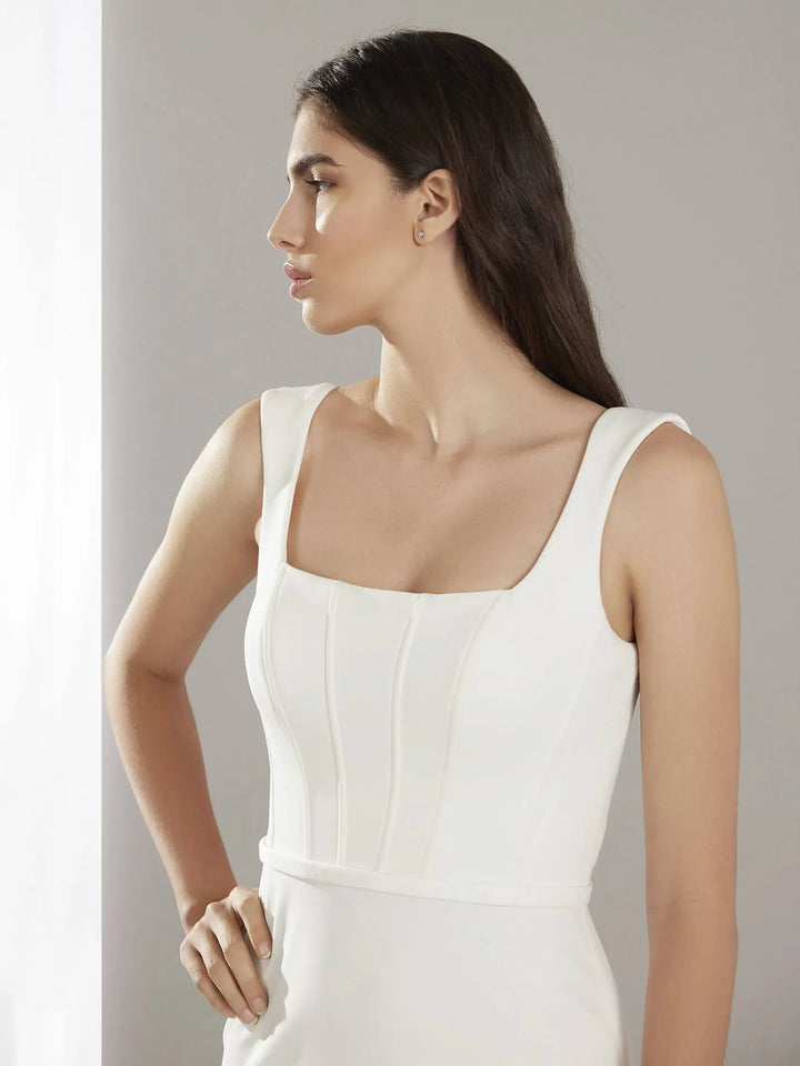close up of pronovias holane ivory crepe fitted wedding dress featuring a square neckline with thick straps