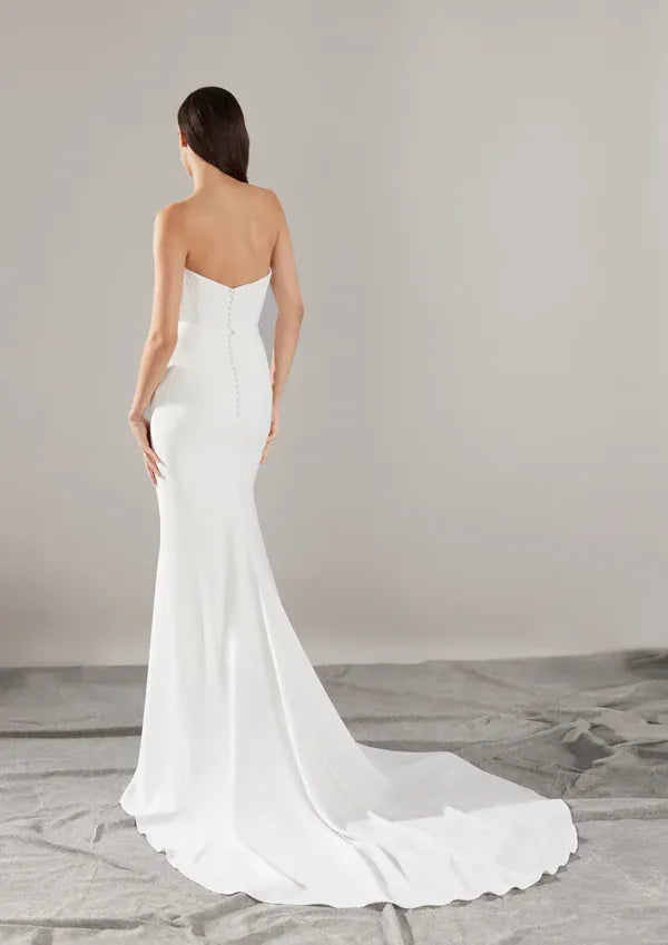 full back of pronovias sincere ivory crepe fitted wedding dress featuring buttons down the back and a short train