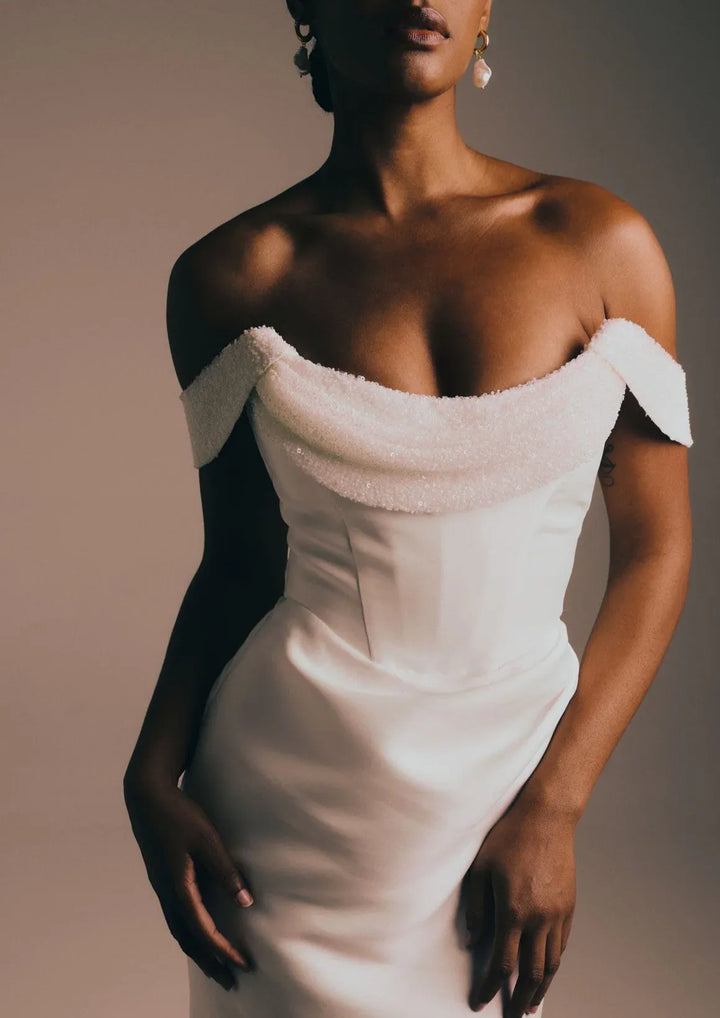 close up of renhue celeste ivory mikado fit and flare wedding dress, showing the beaded drape on the neckline and off the shoulder straps