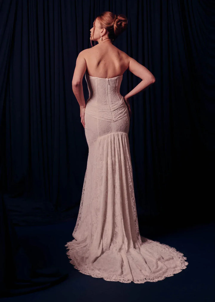 Woman wearing a strapless, floor-length gown against a dark background