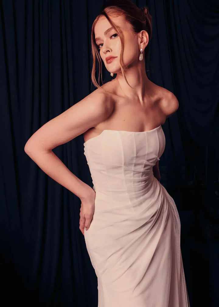 close up of renhue faye ivory tulle sheath wedding dress with a straight neckline and strapless bodice, with draping throughout