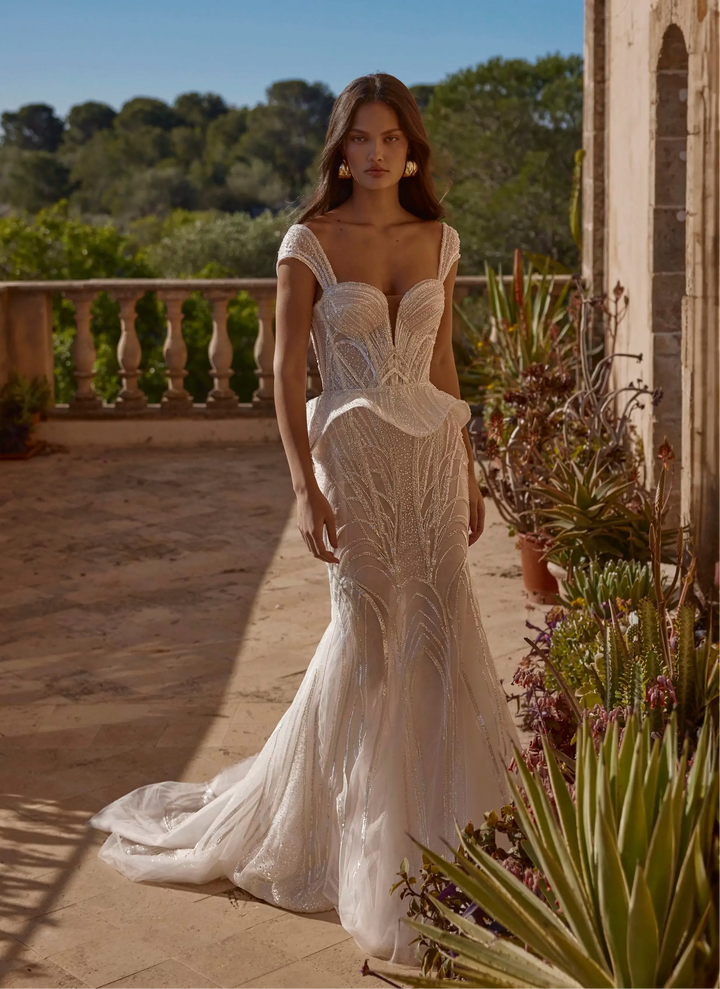 Woman in a white lace wedding dress standing on a balcony with a scenic background