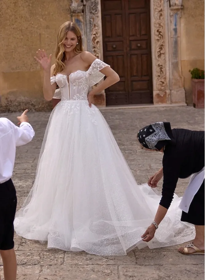Woman in a white wedding dress standing outdoors with children and another person.