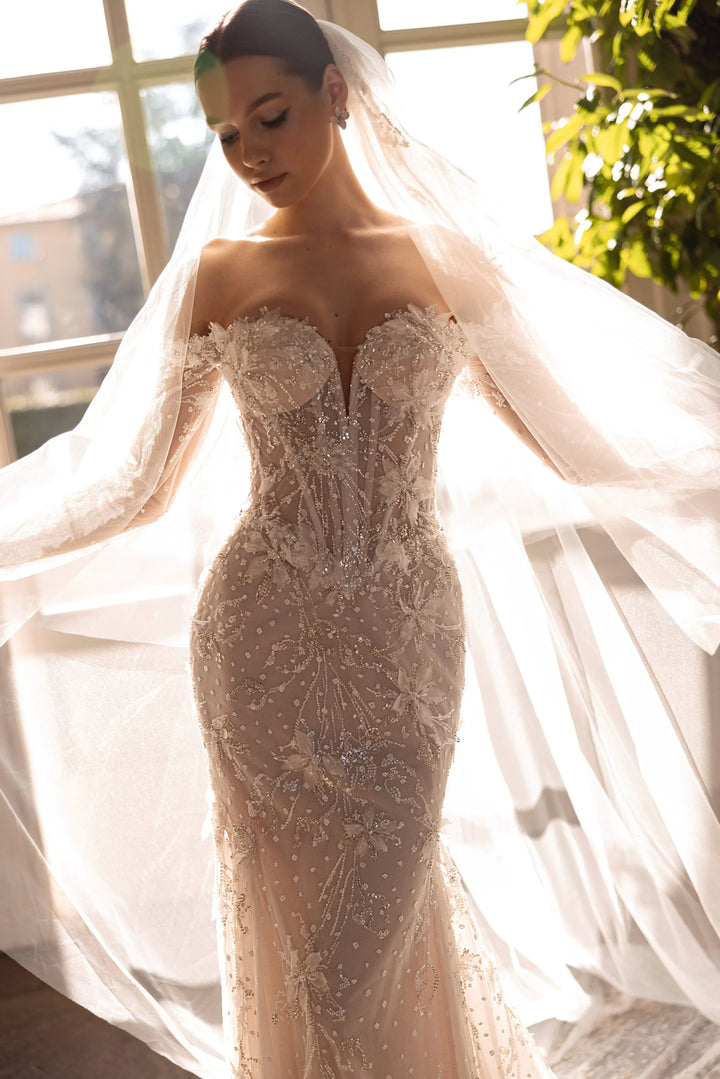 Woman in a sparkling wedding dress with a long veil indoors.