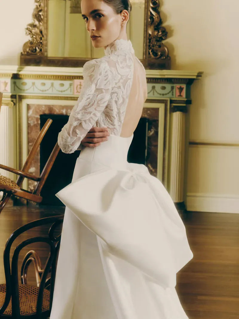 close up of the back of rivini kit ivory satin fitted wedding dress with a lace bodice and matching overskirt with a bow