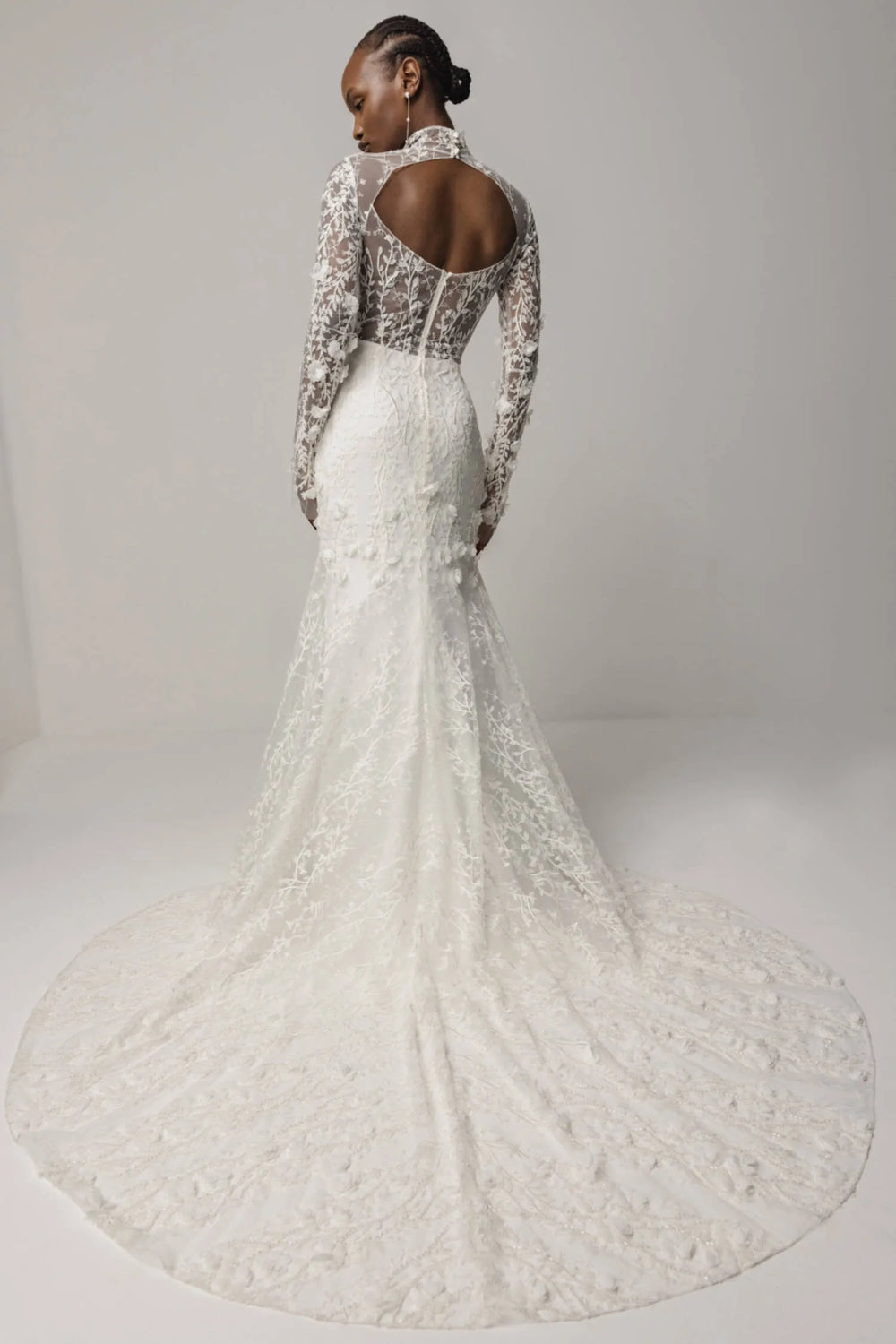 White lace wedding dress with long sleeves on a plain background