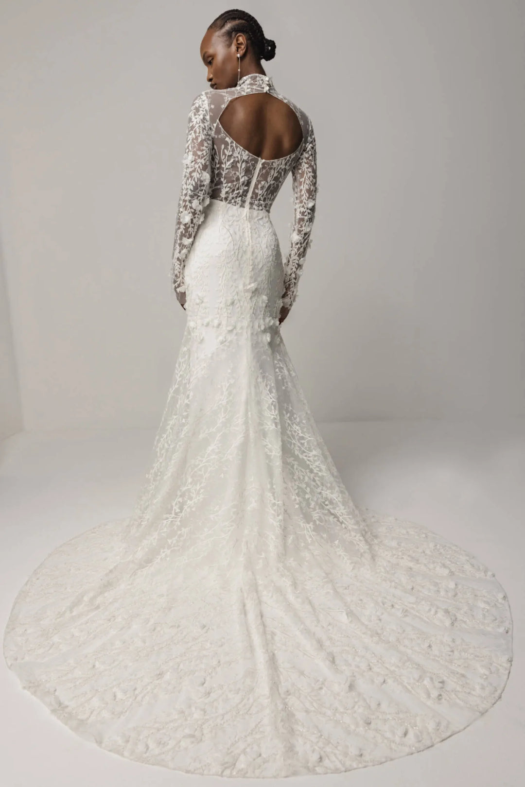 White lace wedding dress with long sleeves on a plain background