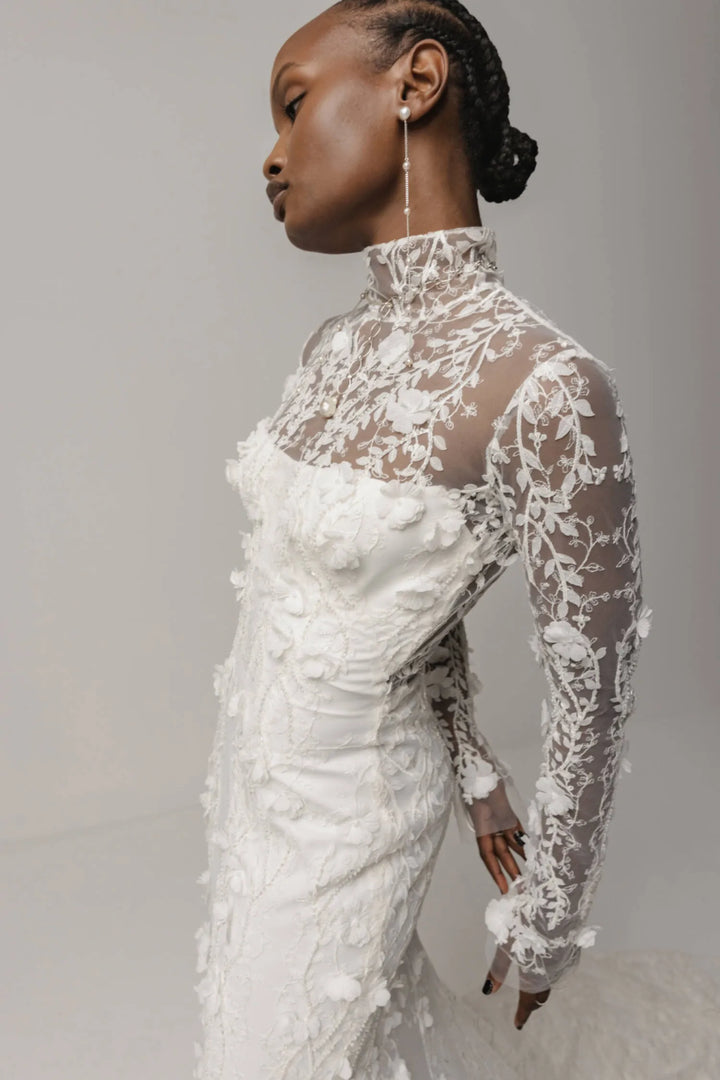 Woman wearing a white lace wedding dress against a gray background