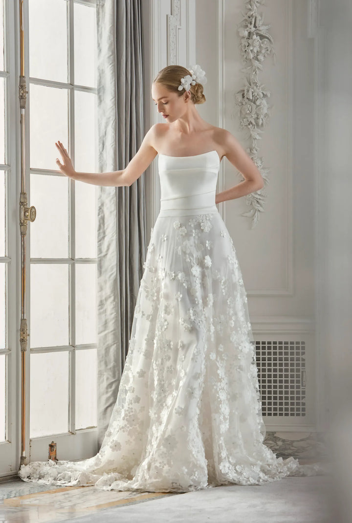 Woman in a white wedding dress standing in a room with large windows and decorative elements.