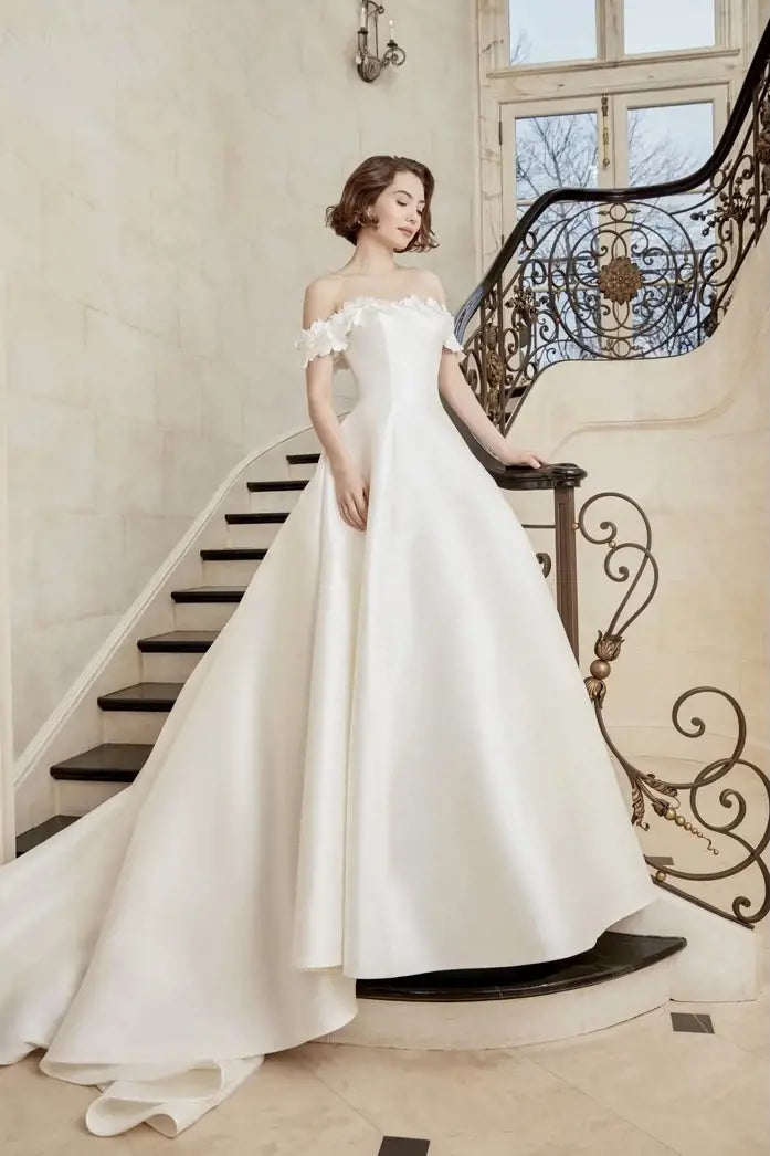 Woman in a white wedding dress standing on a staircase with decorative railings.