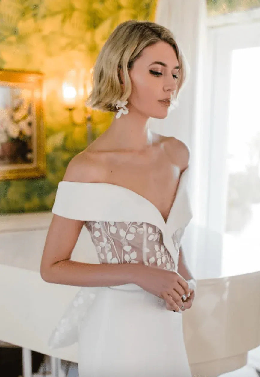 close up of savin london diana v2 ivory crepe fitted wedding dress with lace accents and a bow at the back