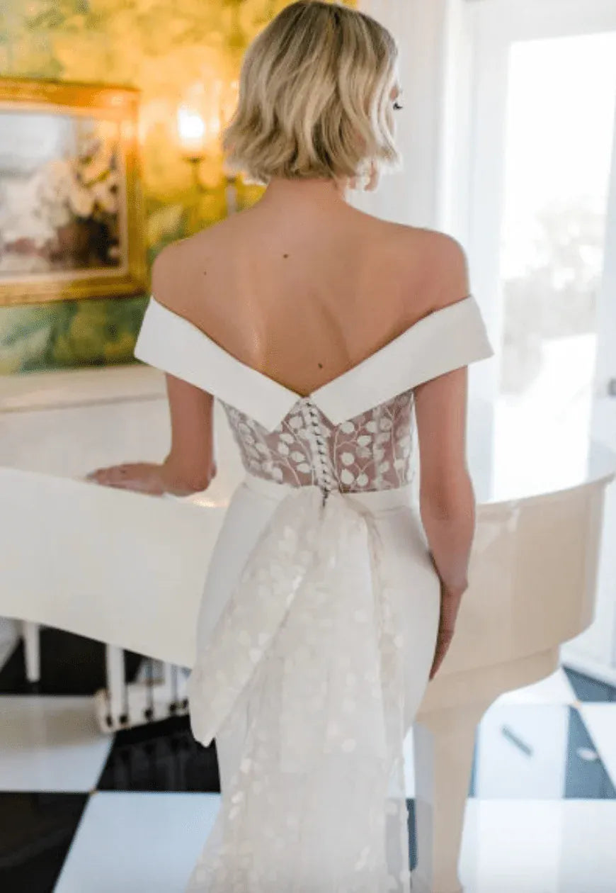 close up of savin london diana v2 ivory crepe fitted wedding dress with lace accents and a bow at the back