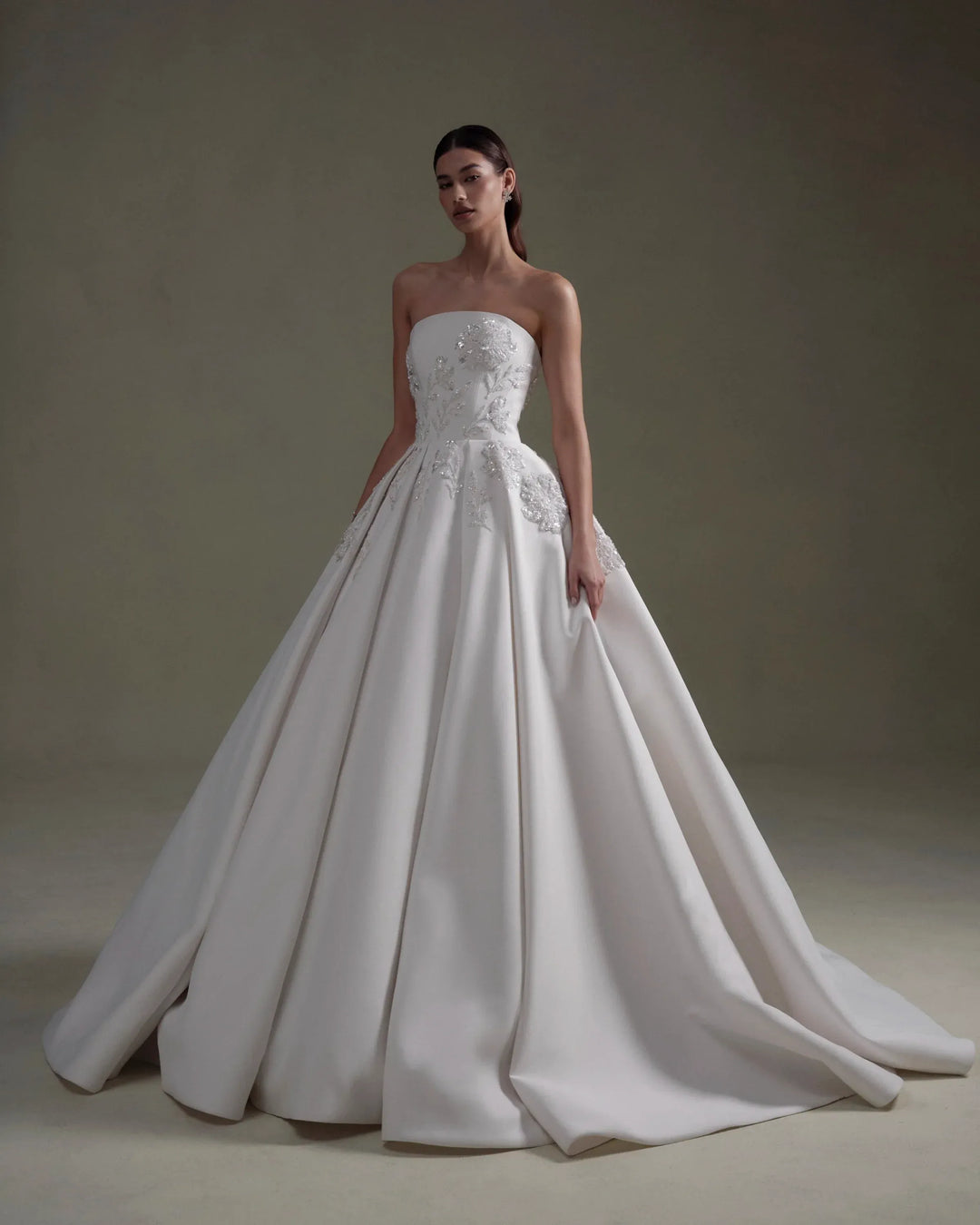 White strapless wedding dress with floral details on a plain background