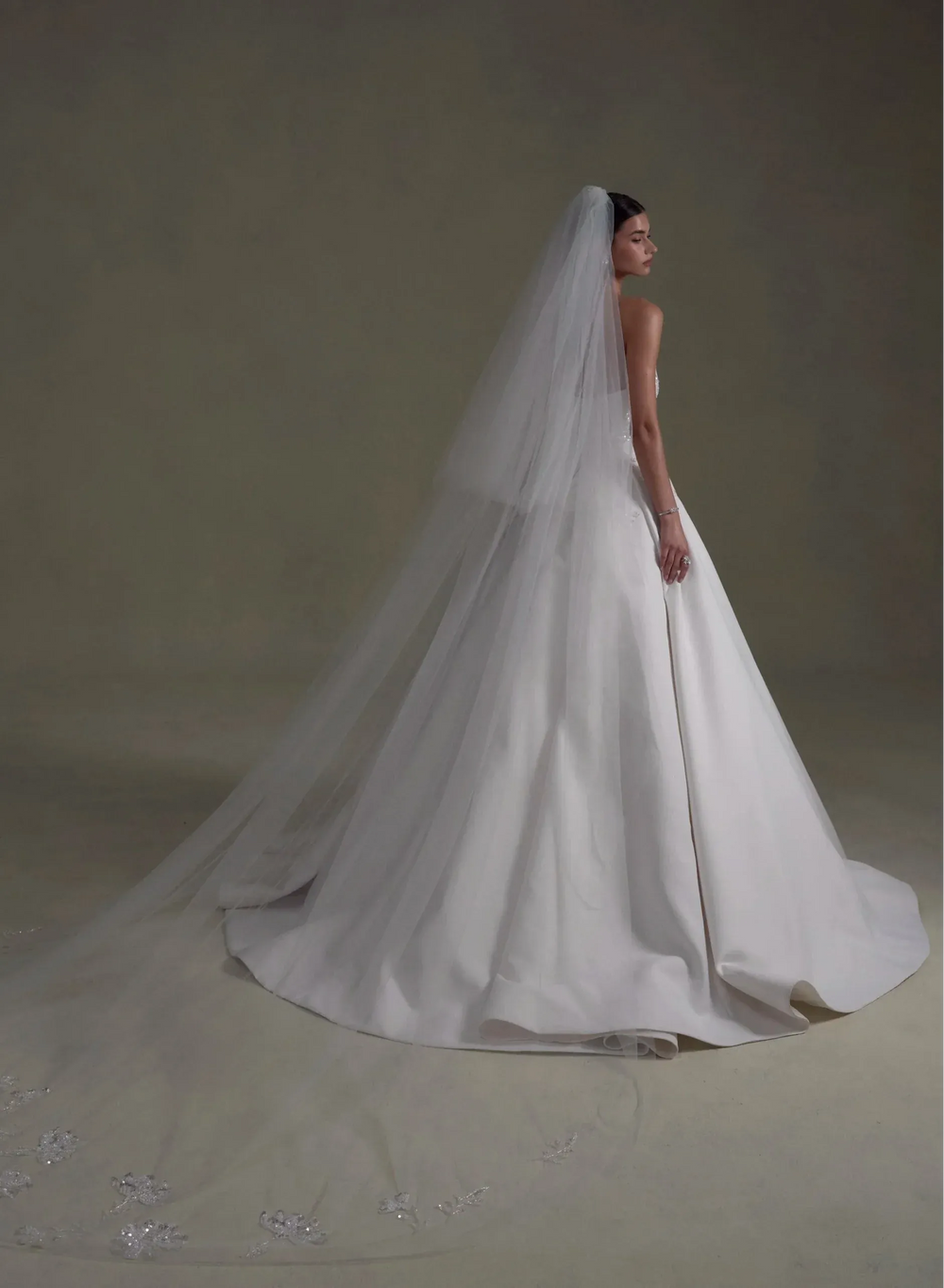 White wedding dress with a long veil on a plain background