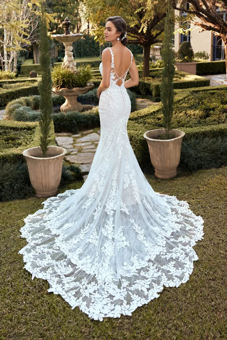 Woman in a white lace wedding dress standing in a garden setting