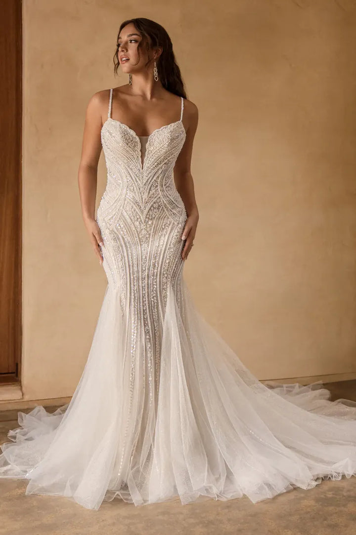 Woman wearing a beaded wedding dress against a beige wall