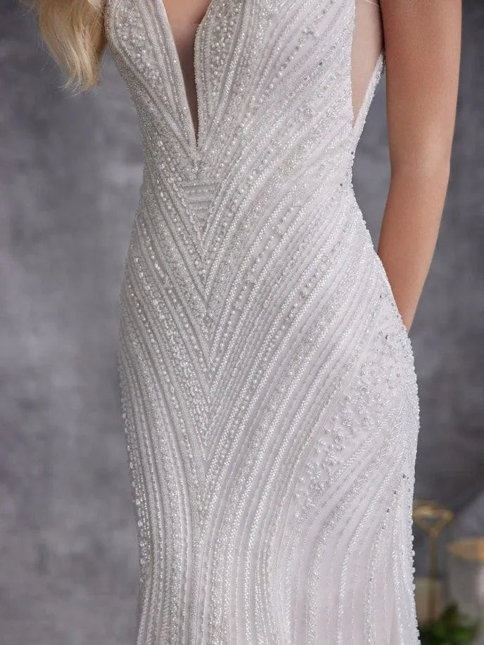Close-up of a sleeveless white or ivory gown with dense beaded vertical stripes and a deep V-neckline, shown on a model against a soft gray studio background.